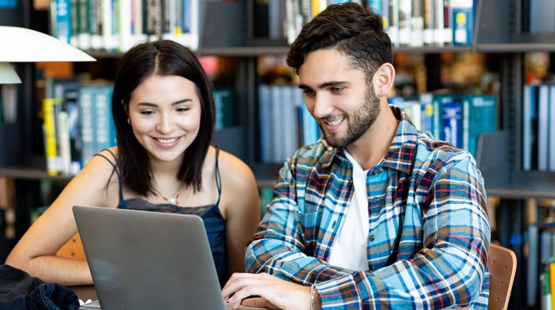 澳门新葡京博彩的男女学生微笑着看着一台笔记本电脑